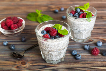 Healthy breakfast or morning with chia seeds vanilla pudding raspberry and blueberry berries on table background, vegetarian food, diet and health concept. Chia pudding with raspberry and blueberry