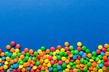 Mixed collection of colorful candy, on colored background. Flat lay, top view. frame of colorful chocolate coated candy