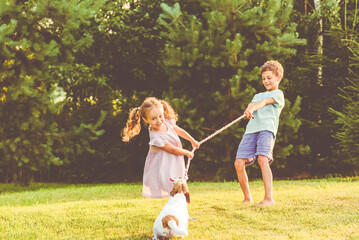 Children playing with their family pet dog tug of war game