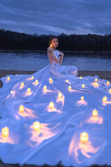 Beautiful woman with candles near lake