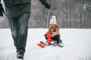 Father with his little daughter is having fun outdoors at winter time