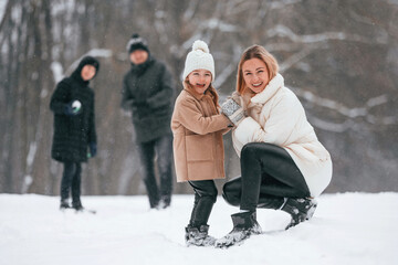 Fototapeta na wymiar Happy family is outdoors, enjoying snow time at winter together