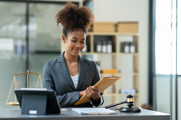 Successful african american woman lawyer or legal advisor working at a desk and holding an envelope of contract documents after signing, law, legal concept.