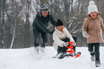 Fototapeta na wymiar Sled ride. Mother and father is with daughter have walk outdoors at the winter season