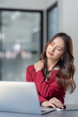 Asian businesswoman sitting in office stressed and fatigued from overwork on financial matters on office desk.