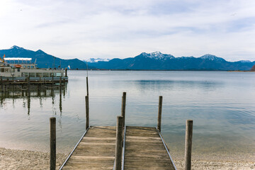Obraz premium View of the Alps.Alpine lake.Lake near the mountains.Snow in the mountains.Wooden pier.Pier at the lake.Travel agency.Holidays in Germany.Popular tourist destination in Germany.Ship at the pier.Lake.
