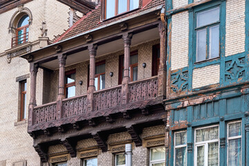An old wooden balcony with columns on the facade of a building.