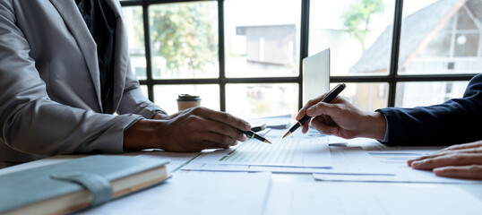 Discussion of young asian businessman or executive discussing numerical data comparing charts and graphs working in business strategy and financial plan for investment profit.