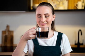 A young woman enjoys fresh fragrant coffee in a modern kitchen