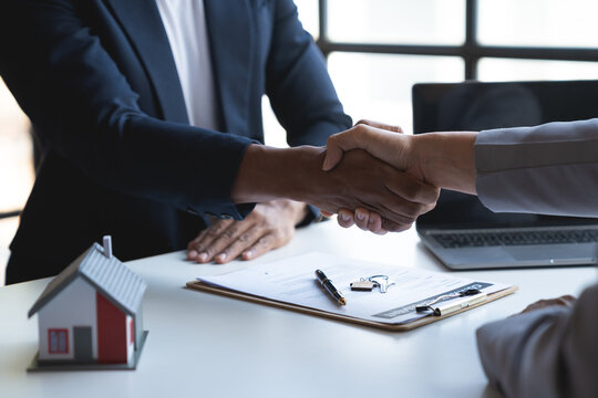 Two Young Asian Businessmen Shake Hands After Signing A Contract To Invest In A Village Project. Real Estate, With Businesswomen Joining In Showing Joy And Clapping In The Office.