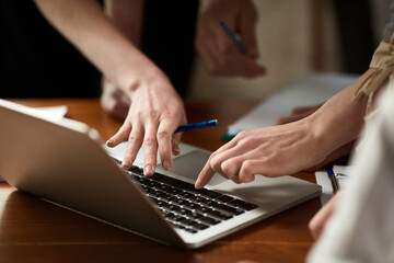 Close-up image of human hands typing on laptop. Business people, employees at meeting in office working with documents and projects. Concept of business, teamwork, career development, brainstorming