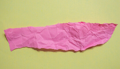 Crumpled pink paper piece on a yellow background. Torn paper background.