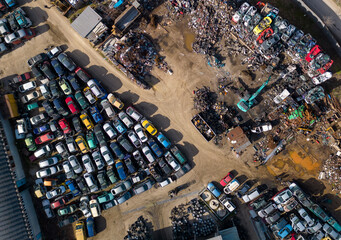 aerial view of a car dump, where a machine is seen separating old cars into scrap.