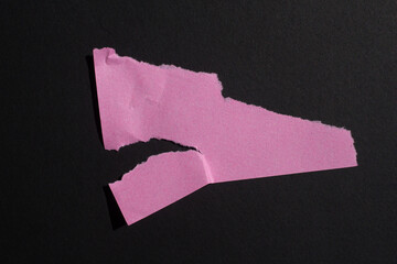 Pink torn paper piece isolated on a black background. Ripped blank paper with copy space for text.