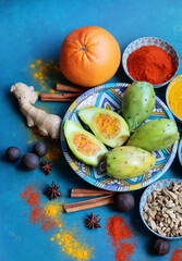 Fototapeta na wymiar Still life with colorful fruit and spices on a table. Top view photo of grapefruit, paprika, turmeric powder, chili pepper, ginger, roses, lavender, anise and cinnamon. Blue background. 