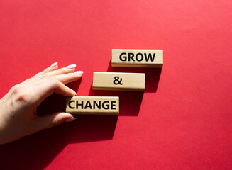 Grow and Change symbol. Wooden blocks with words Grow and Change222. Beautiful red background. Businessman hand. Business and Grow and Change concept. Copy space.