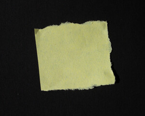 Yellow torn paper piece isolated on a black background. Ripped blank paper with copy space for text.