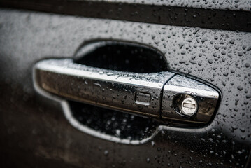 Car door left handle with keyless go sensor. Automatic opening of a car door without a key. The exterior design of a new black luxury car. Closeup.