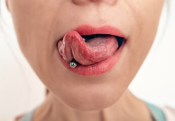 Close-up of woman's mouth with tongue sticking out. Piercing on a woman's tongue. © Todayphoto