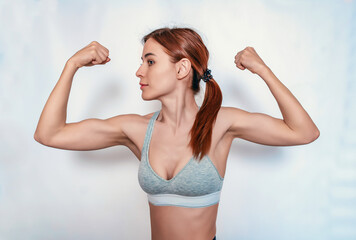 Strong female arm muscles. Sporty woman posing on white background. Fitness classes. Positive body.