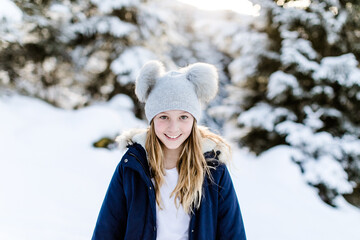 Fototapeta na wymiar Glückliches lachendes Mädchen mit Bommelmütze im Wald im Winter