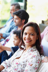 Enjoying a day spent with her family. A smiling young woman looking at the camera while sitting with her family.