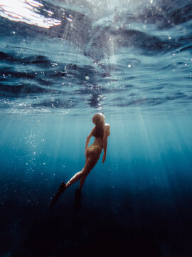 Anonymous woman in mask snorkeling underwater