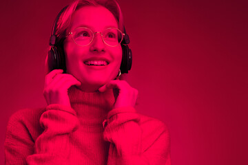 Monochromatic picture of a girl enjoying music isolated on magenta background. Viva magenta, color...