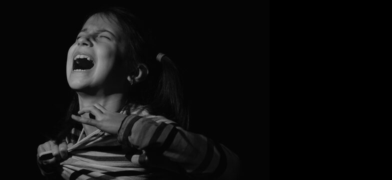 Loss childhood, mental health, depression, panic attacks and anxiety in children. Psychological portrait of nervous child girl screams for help.  Horizontal black and white image.