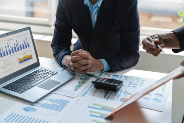 A group of Asian business people are brainstorming and clarifying to analyze the financial report...