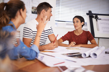 Listening intently to his opinion. a group of young designers working together in an office.