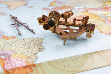 nautical sextant with optics lying on paper world map 