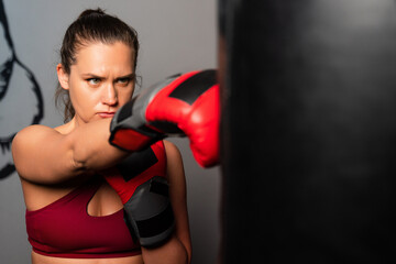 Athletic woman hits a punching bag with gloves