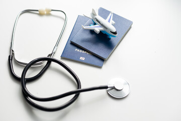 Medical Tourism, medical travel concept. Stethoscope, toy plane and passport on grey background.