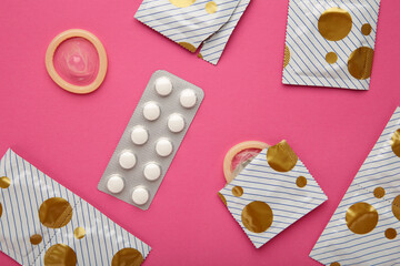 Contraceptive pills and condoms on pink background. Concept of birth control