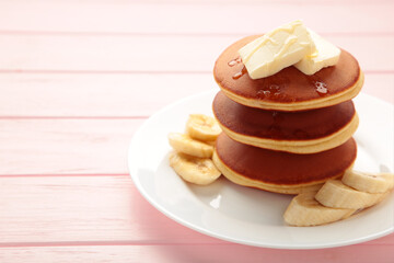 Plate with yummy banana pancakes on pink background. Space for text