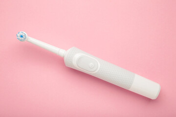 Modern electric toothbrush on pink background. Controlled tool for daily oral care.