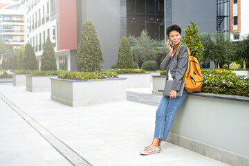 A businesslike modern woman stands on the street of the business center and talks on the phone. 