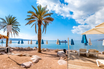 Morning on central public beach of the Red Sea in Eilat - famous tourist resort and recreational city in Israel. Concept of bliss vacation and happy holiday  

