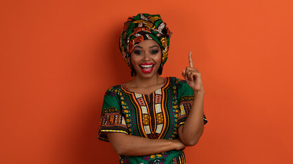 Inspired pretty black woman in african costume showing eureka gesture