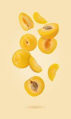 Fresh raw yellow plums falling in the air isolated on yellow illuminating background. Food...