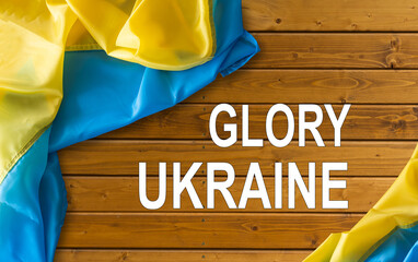 slogan Glory to Ukraine in Ukrainian on waved national flag