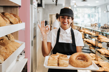 Fototapeta na wymiar Beautiful young and happy female worker working in a modern bakery or fast food restaurant.