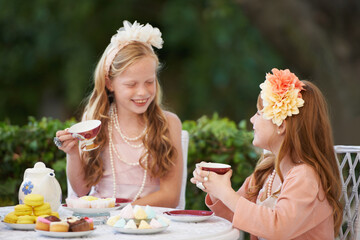 Having a make-believe tea party. Two young girls having a tea party in the backyard.
