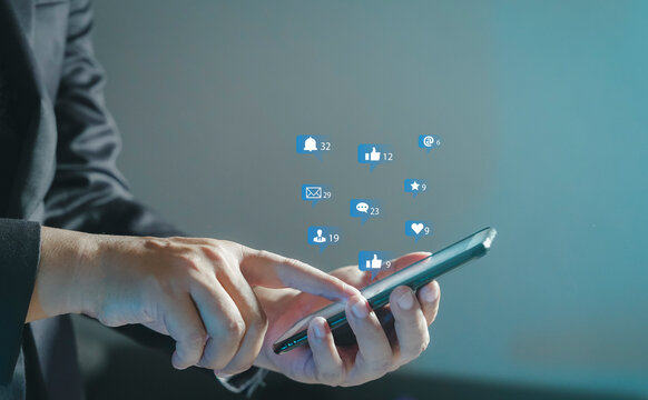 Social media interactions on mobile phone, concept with notification icons of like, message, email, comment and star above smartphone screen, person hands holding device, internet digital marketing