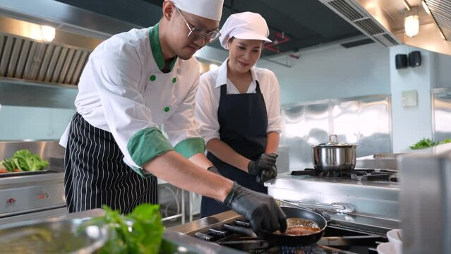 Chef and assistant cooking fish steak in the kitchen.