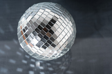 Mirror disco ball on black background. Brilliant decoration, silver decor. Party invitation concept. Copy space.