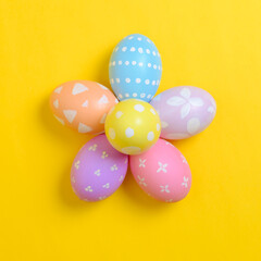 Happy easter holiday celebration concept. Group of painted colourful eggs decoration on a yellow background. Seasonal religion tradition design. Top view, flat lay, copy space.