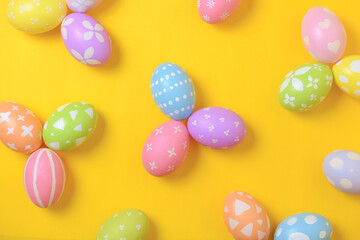 Happy easter holiday celebration concept. Group of painted colourful eggs decoration on a yellow background. Seasonal religion tradition design. Top view, flat lay, copy space.