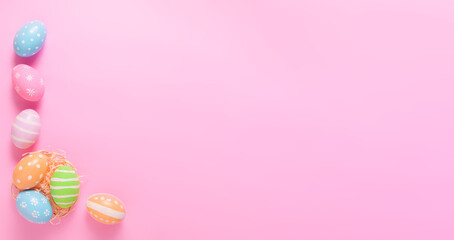 Happy Easter holiday greeting card concept. Colorful Easter Eggs on pastel pink background. Flat lay, top view, copy space.